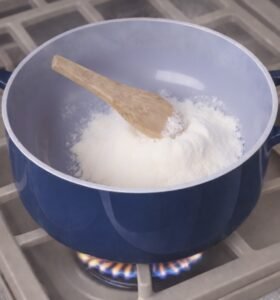 Recette du foufou facile : commencer par chauffer la farine de manioc dans une marmite sur le feu avant d'ajouter l'eau.”